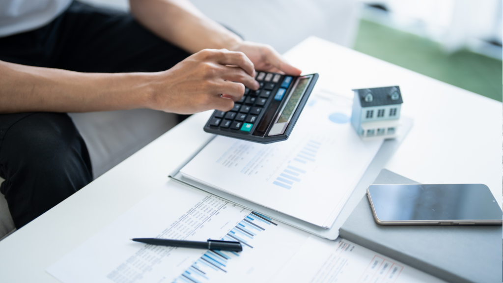 Homebuyer calculating mortgage affordability with calculator, financial documents and house model - Salem Oregon home buying guide